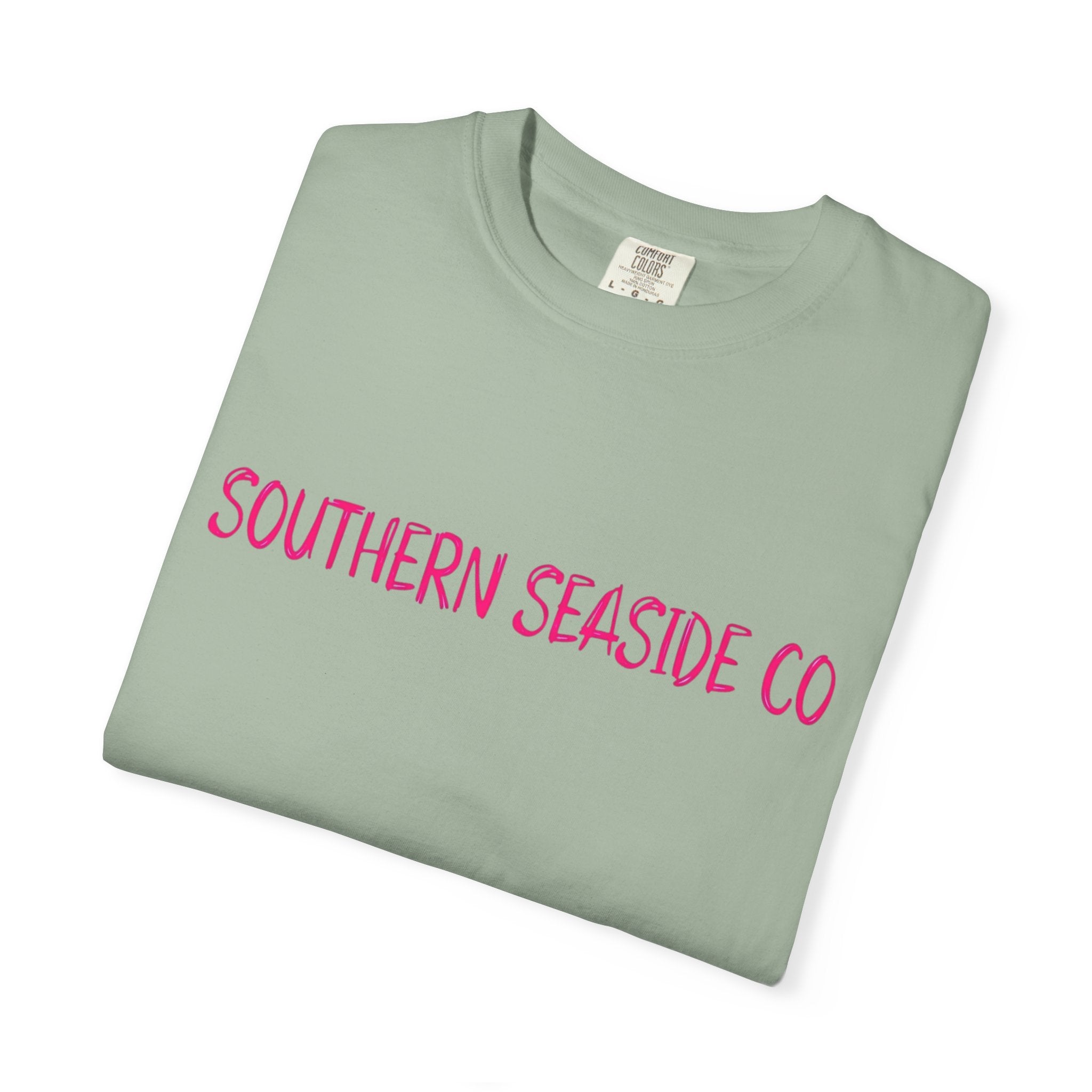Folded light green t-shirt with 'Southern Seaside Co' in pink text on a white background