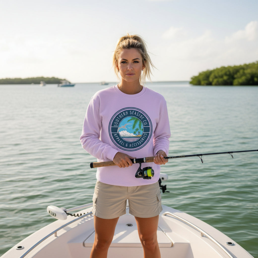 Woman on a boat holding a fishing rod, wearing a pink long-sleeve shirt with a Southern Seaside logo.