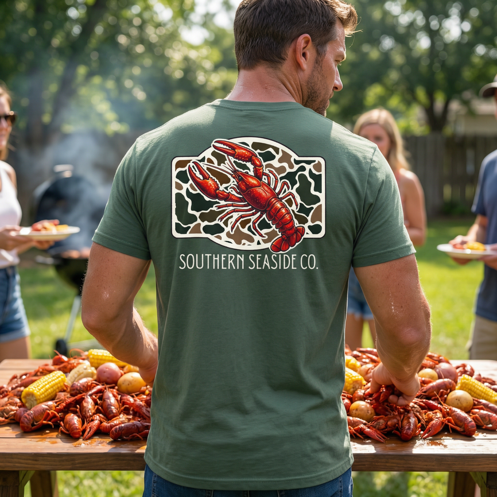 Crawfish t-shirt for men. A Man wearing a green t-shirt with a crawfish design and 'Southern Seaside Co.'logo with new camo print background. crawfish boil.
