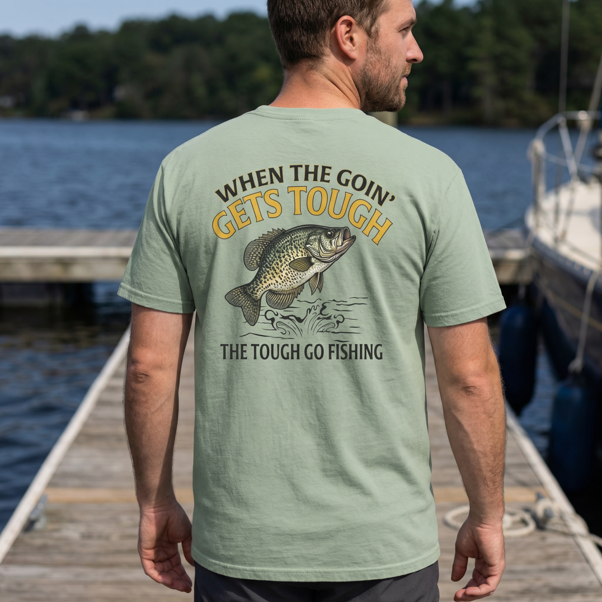 Man wearing a green t-shirt with a crappie fishing graphic and text by a lake.