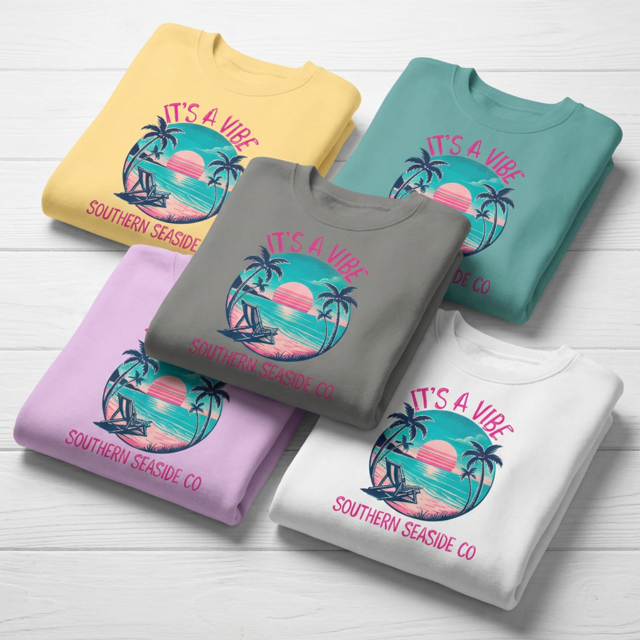 Folded sweatshirts with 'It's a Vibe' design on a wooden surface