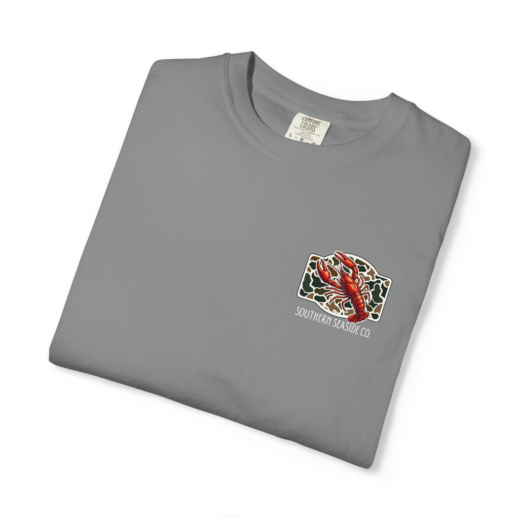 Folded gray comfort color t-shirt with a crawfish graphic and 'Southern Seaside Co' logo with camo print background.