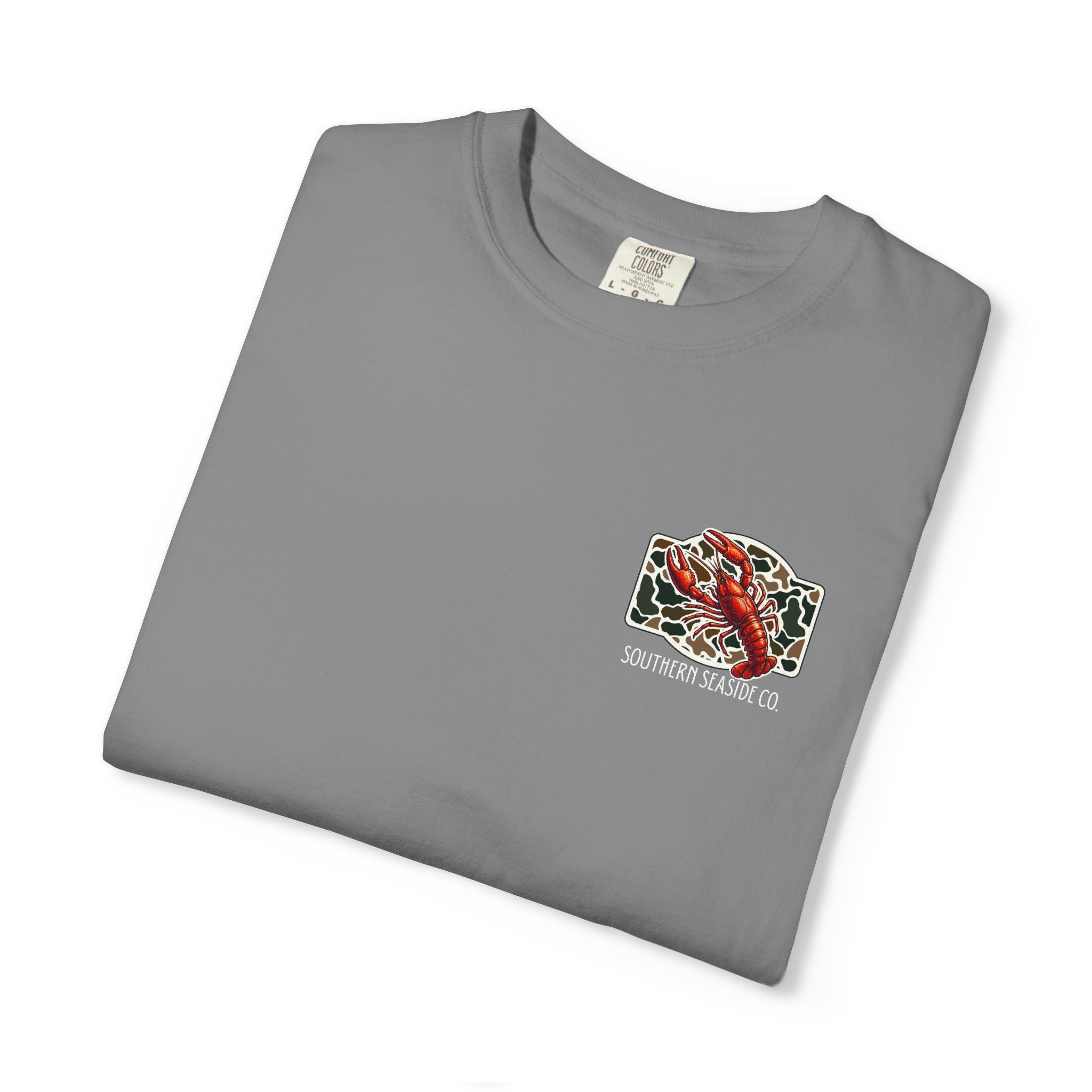 Folded gray comfort color t-shirt with a crawfish graphic and 'Southern Seaside Co' logo with camo print background.