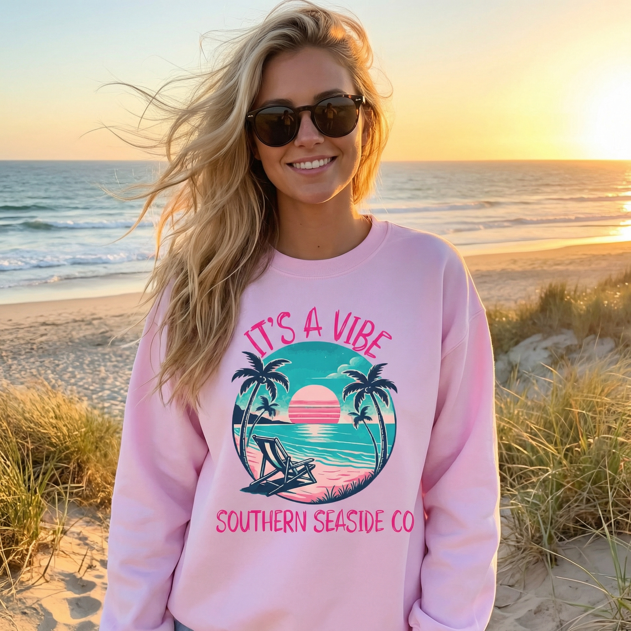 Woman wearing a pink sweatshirt with a beach design on a beach at sunset